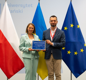 prof. Ewa Szymczak i Wołodymyr Szejko z cerytfikatem członkowstwa w GCUS; w tle flagi Polski, Ukrainy i UE