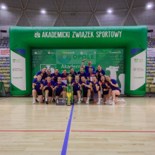 Drużyna z medalami i pucharem na boisku, w tle zielona dmuchana brama z napisem Akademicki Związek Sportowy; fot. Adrian Drążkowski